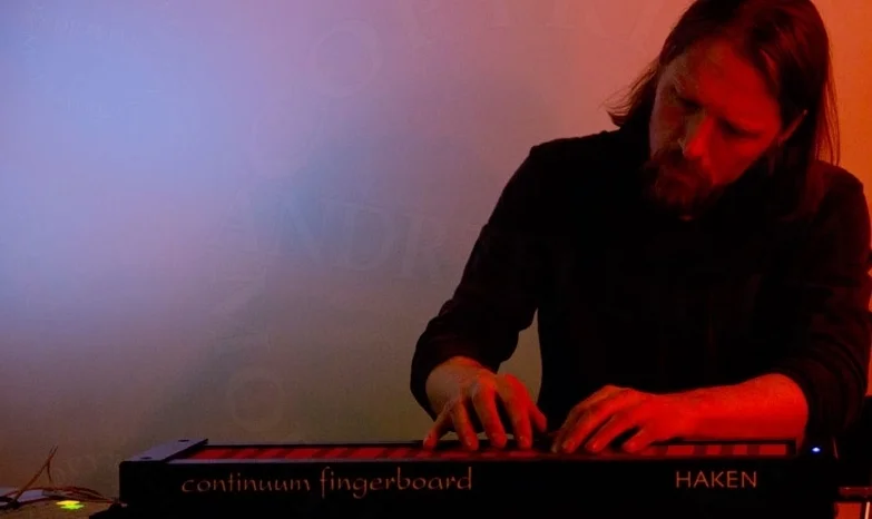 Sarth Calhoun playing a Haken Continuum Fingerboard under red light at the Gralbum launch.